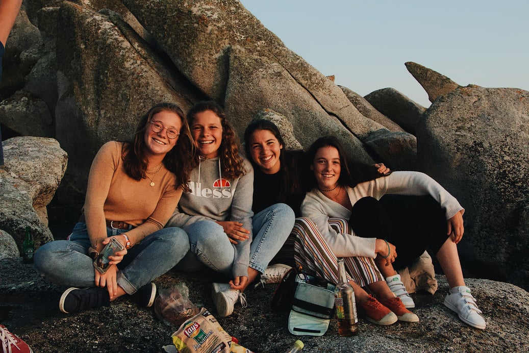 Happy friends resting on rocky coast